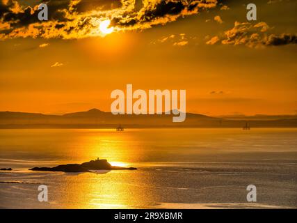 Orangefarbener Sonnenuntergang mit Sonnenuntergang durch dramatische Wolken über Firth of Forth mit Blick auf Fidra Island und Lomond Hills in Fife, Schottland, Großbritannien Stockfoto