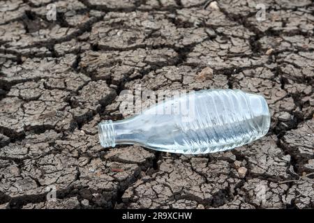 Eine Wasserflasche, einsam auf einem ausgetrockneten Boden. Der Klimawandel bringt Wasserknappheit nach Europa. Jeder Tropfen zählt für unsere Zukunft. Stockfoto