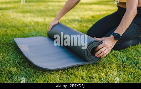 Eine Erntegutfrau, die Yoga auf grünem Gras macht Stockfoto