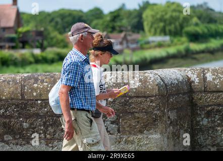 Ein paar Leute gehen über eine Brücke, einer schaut auf eine Karte, vermutlich Touristen, die eine britische Stadt in England besuchen. Stockfoto