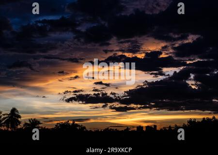 Panorama-Stadtbild bei Sonnenuntergang mit großem Fluss im Vordergrund und strommwolken im Hintergrund in Thailand. Stockfoto