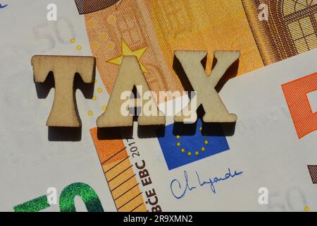 Steuer, Wort in hölzernen Buchstaben isoliert auf dem Hintergrund der Euro-Banknoten Stockfoto