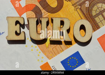 Euro, Wort in hölzernen Buchstaben isoliert auf dem Hintergrund von fünfzig Euro-Banknoten Stockfoto