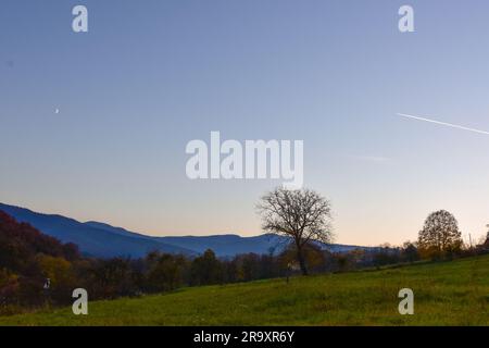 Gemähte Wiese. Ein romantischer Blick auf die Hügel und Berge in der Ferne und eine Szene am Himmel Stockfoto