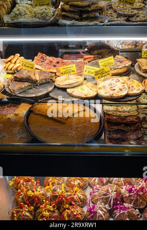 Frisch gebackenes Gebäck und Süßigkeiten in einem Schaufenster in Genua, Italien, einschließlich Farinata, keine Menschen Stockfoto