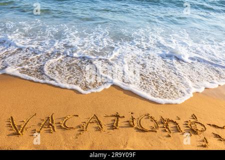 Wellen Sie sich auf einen Sandstrand mit der handgeschriebenen Urlaubserschrift Stockfoto