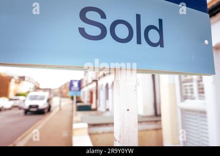 Immobilienmakler VERKAUFT Schild mit entkokkkkketer Straße von Häusern im Hintergrund Stockfoto