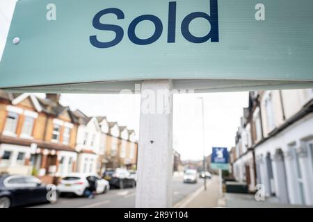 Immobilienmakler VERKAUFT Schild mit entkokkkkketer Straße von Häusern im Hintergrund Stockfoto