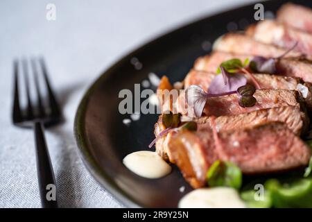 Rinderfilet auf schwarzem Teller mit schwarzer Gabel. Selektiver Fokus. Stockfoto