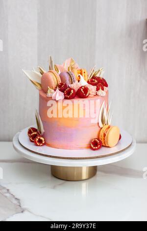 Rosafarbener Kuchen mit frischen Himbeeren, Schokoladenblüten, Makronen und Baiser Stockfoto