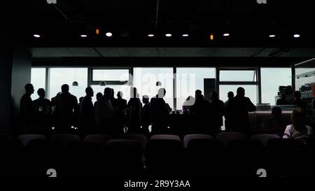 Viele Geschäft Leute stehen in einer Linie gegen das Zimmer mit einem großen Fenster, Blick auf die Stadt Stockfoto