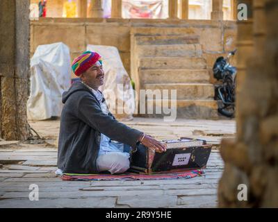 Jaisalmer, Indien - 24. Dezember 2022: Unidentifizierte Nomaden singen und spielen Harmonium im Ghadisar Lake in Jaisalmer, Indien. Harmonium, uralter Instr Stockfoto