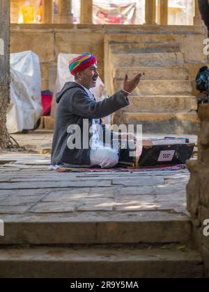 Jaisalmer, Indien - 24. Dezember 2022: Unidentifizierte Nomaden singen und spielen Harmonium im Ghadisar Lake in Jaisalmer, Indien. Harmonium, uralter Instr Stockfoto