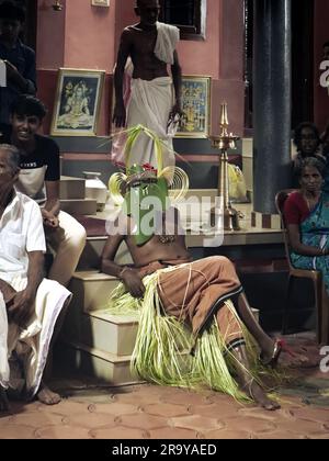 Ein maskierter Theyyam-Künstler, der im Tempel auftritt und während einer Festveranstaltung in der Öffentlichkeit den Geist eines göttlichen gottes repräsentiert Stockfoto