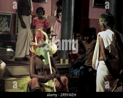 Ein maskierter Theyyam-Künstler, der im Tempel auftritt und während einer Festveranstaltung in der Öffentlichkeit den Geist eines göttlichen gottes repräsentiert Stockfoto