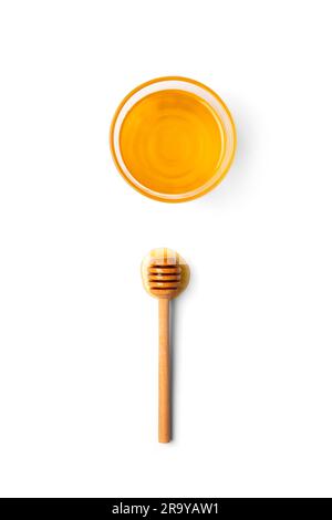 Kreative Komposition, ein hölzerner Pendelarm liegt in einem Tropfen Honig und einer Schüssel mit Honig auf weißem Hintergrund in einem Kopierbereich von oben Stockfoto