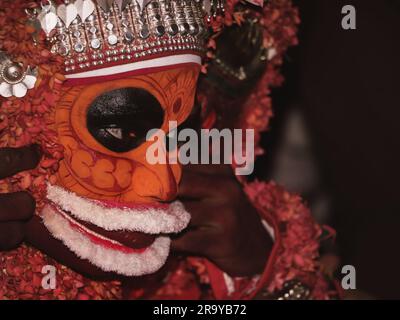 Ein Porträt eines Theyyam-Künstlers aus der Nahaufnahme, dekoriert mit Gesichtsausdruck und Ornamenten für Leistung in einem traditionellen hinduistischen Stil Stockfoto