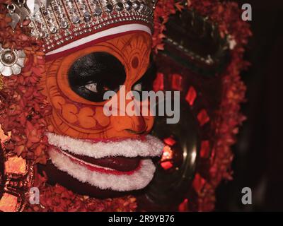 Ein Porträt eines Theyyam-Künstlers aus der Nahaufnahme, dekoriert mit Gesichtsausdruck und Ornamenten für Leistung in einem traditionellen hinduistischen Stil Stockfoto