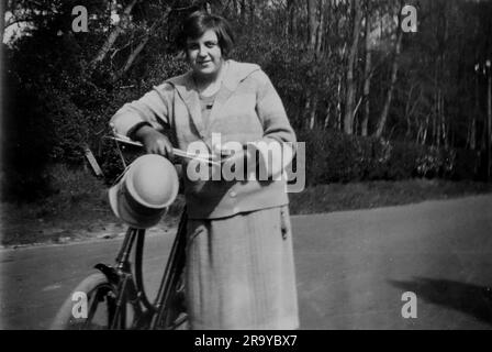Eine Dame, die auf einem Fahrrad pausiert. Foto aus einem Familienalbum mit Schnappschüssen, die in den 1920er Jahren hauptsächlich im Vereinigten Königreich aufgenommen wurden. Die Familie lebte in Witley, Surrey, und hatte Verbindungen zum Militär. Stockfoto