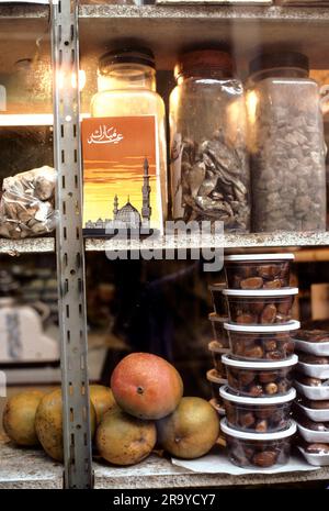 Englisch-muslimische Schaufenster. Eine Postkarte der Medina-Moschee mit Minaretten zwischen den Gläsern mit getrocknetem Fisch und Datteln. Multi Ethno Supermarkt, Brick Lane, East London. Whitechapel, London, England, 1977 1970er Jahre Großbritannien HOMER SYKES Stockfoto