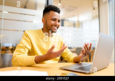 Ein junger indischer Mann hielt Videoanrufe, winkte, begrüßte Teilnehmer online, männlicher Student nahm an Online-Kursen Teil, beinhaltete virtuelle Treffen, sprach und Gesten Stockfoto