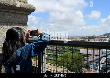 Eine Touristin fotografiert mit einem Smartphone über dem Wachzaun und blickt auf Porto, Portugal Stockfoto