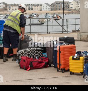 Hugh Town, St. Marys, Scilly-Inseln, Großbritannien. 10. Juni 2023 Gepäck von Fährpassagieren wird am Kai von Hugh Town mit Blick auf Town Beach, St. Stockfoto
