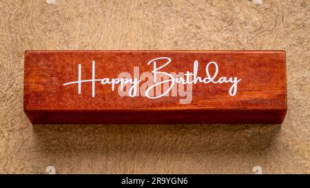 Happy Birthday Text on wood Block against handmade Rindenpapier in Earth Colones, Grußkonzept Stockfoto