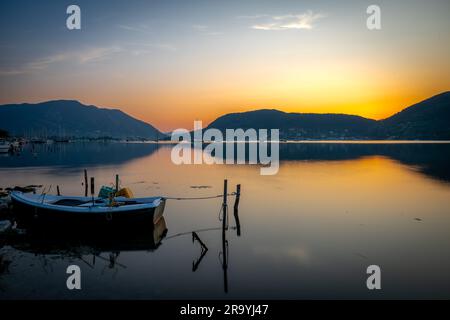 Eine lange Sonnenaufgang-Meereslandschaft mit einem kleinen Holzboot in einer Bucht. Stockfoto