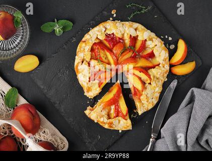 Hausgemachte Torte-Pfirsich-Galette – offener Kuchen mit frischen Bio-Früchten. Nahaufnahme. Dunkel launisch, unauffällig. Zur Ansicht Stockfoto