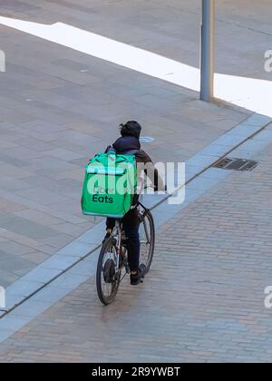 Mobile Lebensmittellieferung nach Zyklus für Uber Eats. Eine beliebte App, mit der Kunden Essen zum Mitnehmen zu Hause bestellen können. Stockfoto