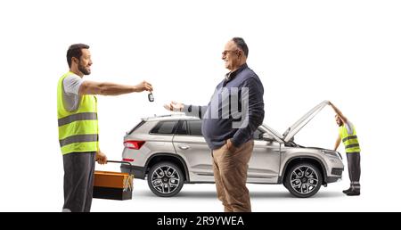 Mechaniker überprüft einen SUV und gibt einem erwachsenen Mann Autoschlüssel, isoliert auf weißem Hintergrund Stockfoto
