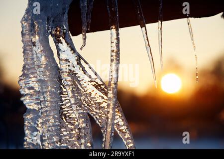 Extreme Nahaufnahme von Eiszapfen mit Sonnenuntergang im Hintergrund Stockfoto