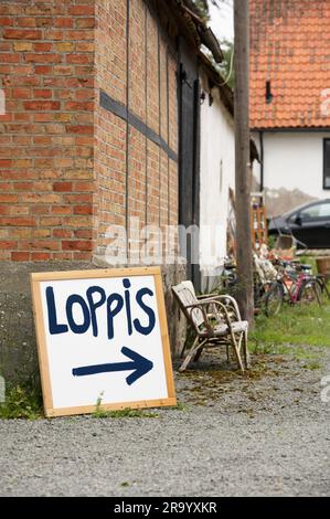 Schild auf dem Boden gegen eine Ziegelstruktur, die zum Flohmarkt zeigt. Schweden. Stockfoto