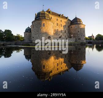 Spiegelbild des Schlosses in einem ruhigen und ruhigen Graben vor klarem blauen Himmel. Örebro, Schweden. Stockfoto