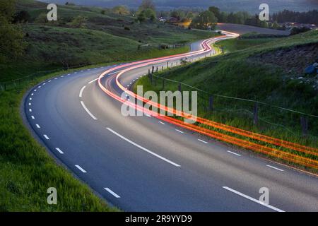 Blick von oben auf leichte Wege von sich bewegenden Fahrzeugen auf Landstraßen. Skane, Schweden. Stockfoto