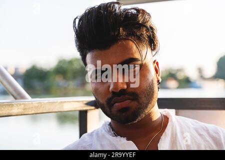Porträt eines jungen, gutaussehenden pakistaners, der während der Sommerferien auf einem Fluss auf einem Boot segelte Stockfoto