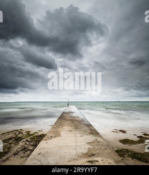 Sturmwolken und Steg am Meer. Stockfoto