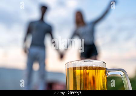 Nahaufnahme eines Glases Bier vor einem jungen, multiethnischen Paar von Liebhabern, verschwommen im Hintergrund Stockfoto