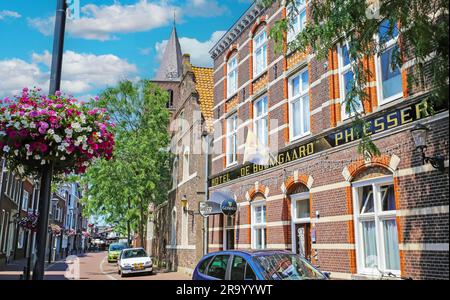Boxmeer, Niederlande - Juli 9. 2023 Uhr: Wunderschöne holländische Straße, grüne Bäume, traditionelle alte Backsteinhausfassade des de Boomgaard Hotels Stockfoto