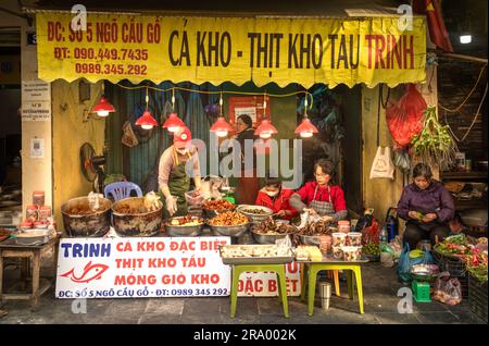 Vietnamesische Frauen bereiten geschmorten Fisch, Schweinefleisch und andere Gerichte in einem Imbissladen in der Altstadt von Hanoi, Vietnam, zu. Stockfoto