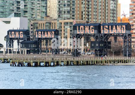 Das ikonische Long Island Schild vom Wasser aus mit modernen Gebäuden im Hintergrund, New York City Stockfoto