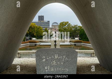 Hiroshima Opfers Memorial Cenotaph im Hiroshima Peace Memorial Park, Japan, mit einer Bombenkuppel im Hintergrund Stockfoto