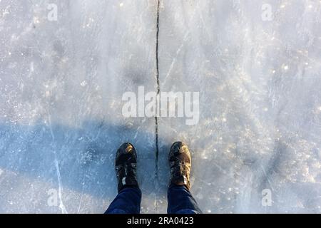 Eis und Füße auf beiden Seiten des Risses, aufgenommen auf einem See in Flevopark, Amsterdam, Februar 2021 Stockfoto