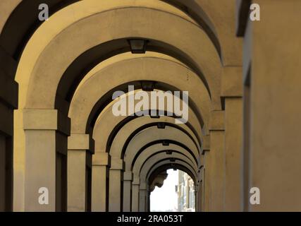 Korridor mit Reihen von Säulen und Bogen im Sonnenlicht, Detail des Korridors entlang des Flusses Arno, in der Nähe der Ponte Vecchio, Florenz Stockfoto