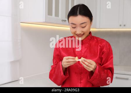 Asiatische Frau hält leckeren Glückskeks mit Vorhersage in der Küche. Platz für Text Stockfoto