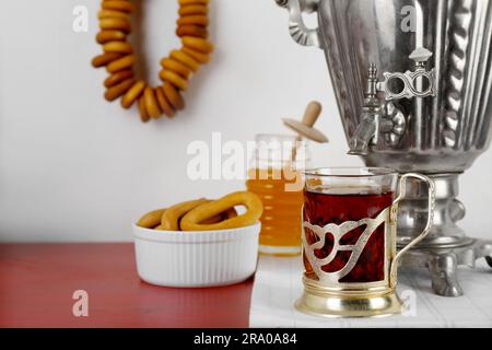 Zusammensetzung mit köstlichen ringförmigen Sushki (trockene Bagels) und Tee auf braunem Tisch nahe der weißen Wand Stockfoto