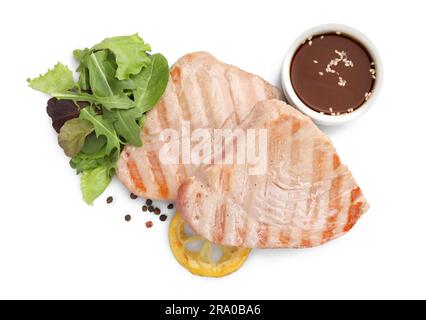 Köstliche Thunfischsteaks mit Salat, Sauce und Zitrone isoliert auf Weiß, Draufsicht Stockfoto