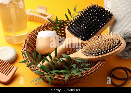 Holzbürsten und verschiedene Haarprodukte auf orangefarbenem Hintergrund Stockfoto