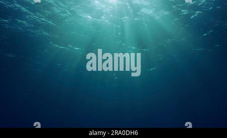 Blick auf Sonnenlicht aus blauem Abgrund, Zeitlupe. Das Licht filtert durch blaues Wasser nach unten. Unterwassersonnenstrahlen im tiefen Ozean. Unterwasser-Sonnenlicht scheint Stockfoto